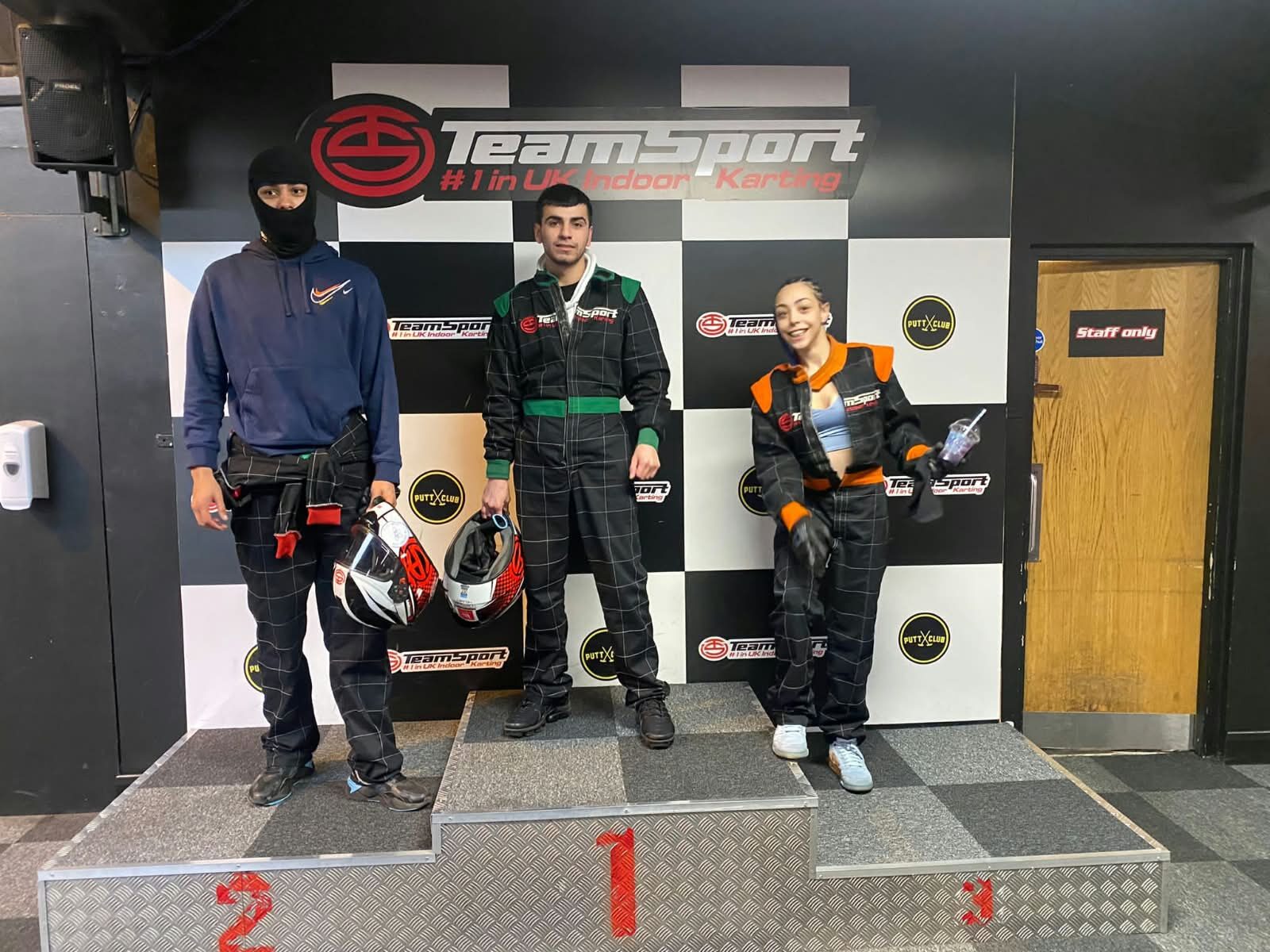 Young people on the winners' podium at an indoor karting day
